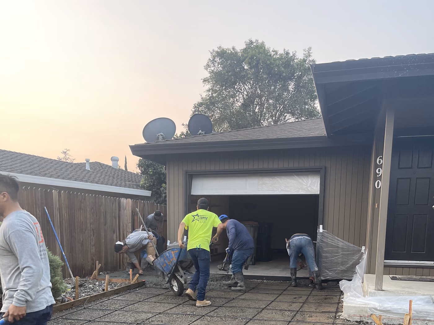 Crew setting reinforcement across a prepared driveway base