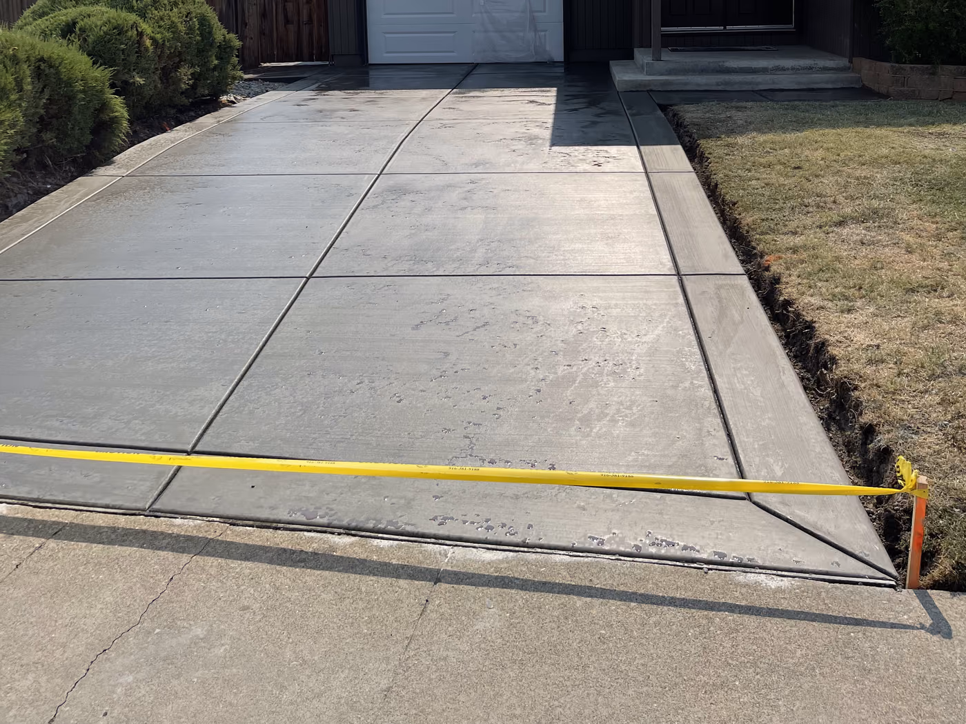 Finished concrete driveway running to an attached garage